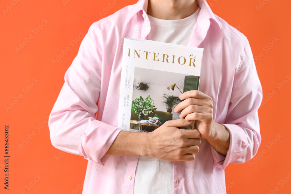 Young man with magazine on orange background, closeup