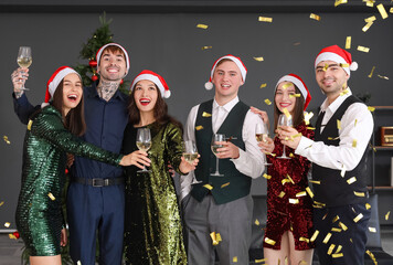 Canvas Print - Young coworkers with champagne and confetti celebrating New Year at corporate party in office