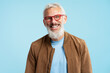 © Maria Vitkovska - Portrait handsome smiling 50 years old mature man with stylish gray hair wearing red hipster glasses looking at camera isolated on blue background. Vision concept