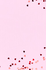 Wall Mural - Metallic red confetti in a heart shape on a pink background. Place for text.