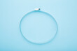 New metal hose clamp on light blue table background. Pastel color. Closeup. Top down view.