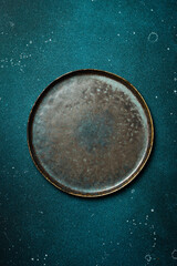 Wall Mural - A dark stone plate on a blue stone table. Free copy space. Top view.