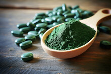 Chlorella or spirulina tablets and powder in wooden spoon on wooden background Nutritional supplement, Detox superfood