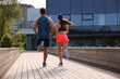 Healthy lifestyle. Couple running outdoors on sunny day, back view. Space for text