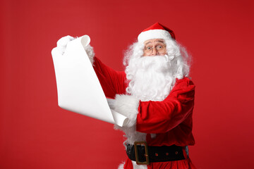 Sticker - Merry Christmas. Santa Claus holding wishlist on red background