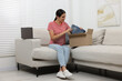 © New Africa - Young woman with just unpacked new jeans on sofa at home. Online shopping