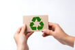© natalystudio - hand holding paper card with recycle logo on white background. Generated AI