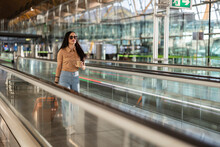 Beautiful Woman With Coffee Cup And Suitcase Moving On Travelator