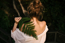 Young Blond Woman Holding Fern Covering Her Shoulder