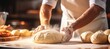 © Andrei - Skilled baker kneading dough in bakery for bread baking bright photo with blurred background