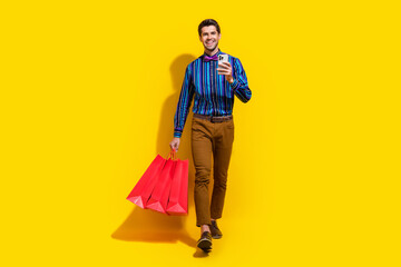 Canvas Print - Full size photo of clever guy dressed striped shirt go with shopping bags order clothes on smartphone isolated on yellow color background