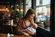 Beautiful young mother with her newborn baby in cafe. Motherhood concept.