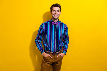 Poster - Photo of confident gentleman dressed striped shirt tie bow standing hold arms in pockets isolated on vivid yellow color background