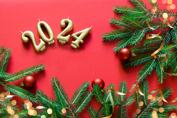 Wall Mural - Happy new year frame. Christmas card banner with Christmas tree branches and gold candle numbers 2024, golden decorative ribbon. Red background. Mockup.