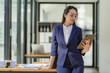 © ArLawKa - Professional business woman, corporate marketing manager, female worker holding a digital tablet is reading information of a new startup on the tablet and analyzing business strategy and planning.