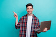 © deagreez - Photo of good mood positive guy wear checkered shirt texting modern device pointing empty space isolated blue teal color background