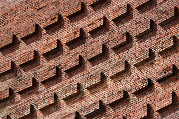 Old red brick wall with protruding blocks as background