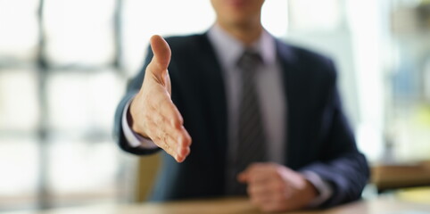 Wall Mural - Businessman in suit extending his hand for handshake to partner at work in office closeup. Successful customer service concept