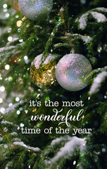 Wall Mural - it's the most wonderful time of the year - inspiration quote. shiny christmas balls on snowy fir tree outdoor. Winter nature background. festive winter season. Christmas and new year holidays