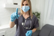 A female doctor wearing rubber gloves shows a gesture of holding something.