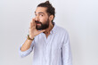 © Krakenimages.com - Hispanic man with beard wearing casual shirt hand on mouth telling secret rumor, whispering malicious talk conversation