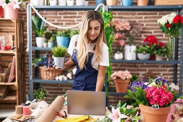 Poster - Young blonde woman florist using laptop holding plant at florist