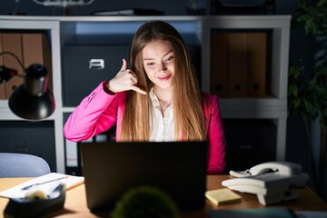 Sticker - Young caucasian woman working at the office at night smiling doing phone gesture with hand and fingers like talking on the telephone. communicating concepts.