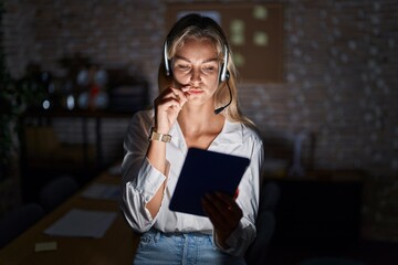 Poster - Young blonde woman working at the office at night mouth and lips shut as zip with fingers. secret and silent, taboo talking