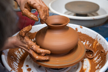 A piece of ceramic taking shape on the wheel by expert hands.