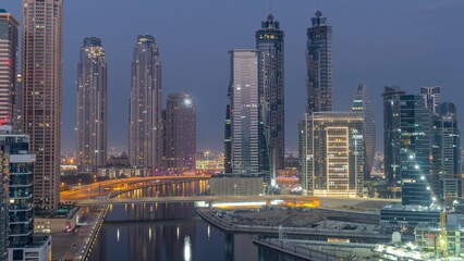 Wall Mural - Cityscape with skyscrapers of Dubai Business Bay and water canal aerial night to day timelapse.