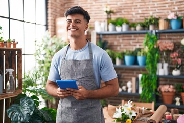 Canvas Print - Young hispanic man florist smiling confident using touchpad at flower shop