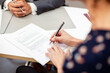 © PhotoAlto - High angle view close up of adult woman signing a contract during meeting