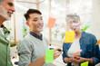 © PhotoAlto - Coworker brainstorming while writing on sticky notes on glass wall