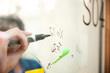 © PhotoAlto - Close up of businessman writing on glass wall with black marker