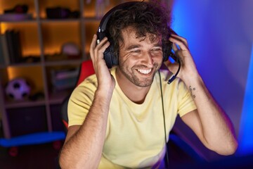 Canvas Print - Young hispanic man streamer smiling confident sitting on table at gaming room