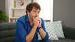 © Krakenimages.com - Young hispanic man sitting on sofa with serious expression at home
