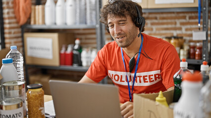 Wall Mural - Young hispanic man volunteer writing on clipboard having video call at charity center