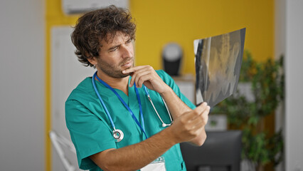 Canvas Print - Young hispanic man doctor looking xray at clinic