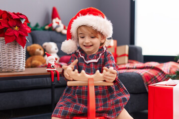 Sticker - Adorable caucasian girl playing with reindeer rocking by christmas decoration at home