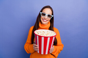 Poster - Photo of smiling happy woman wear orange knitted pullover 3d glasses for movies holding popcorn isolated on violet color background