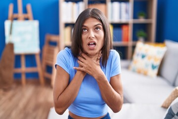 Canvas Print - Brunette young woman sitting on the sofa at home shouting and suffocate because painful strangle. health problem. asphyxiate and suicide concept.