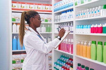 Wall Mural - African american woman pharmacist writing on document at pharmacy