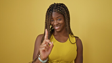 Wall Mural - African american woman smiling confident with finger up over isolated yellow background