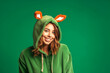 Portrait of happy woman wearing christmas deer costume with pastel background