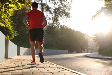 Canvas Print - Man running outdoors on sunny day, back view. Space for text