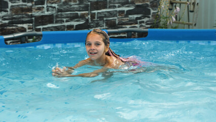 cute school age girl swimming in a pool with beautiful blue water. cute 8-9 year old girl relaxing i