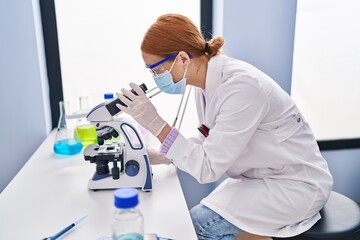 Sticker - Young caucasian woman scientist wearing medical mask using microscope at laboratory