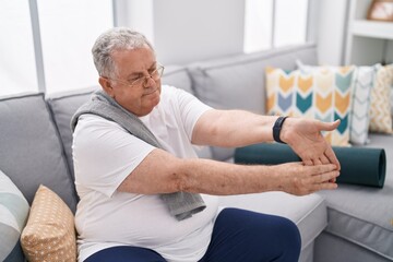 Sticker - Middle age grey-haired man stretching arm sitting on sofa at home