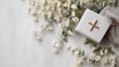 A golden Christian cross on a box with white flowers. Background with space to copy.