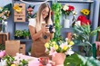 Young beautiful hispanic woman florist make photo to bouquet of flowes gift at flower shop